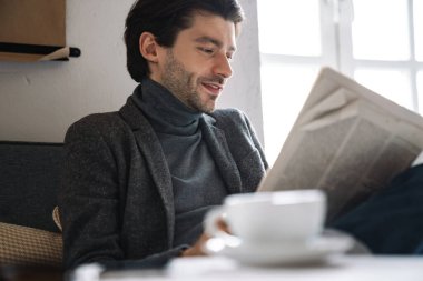 Kafkasyalı yakışıklı bir iş adamının parlak modern kafede oturup gazete okuması.