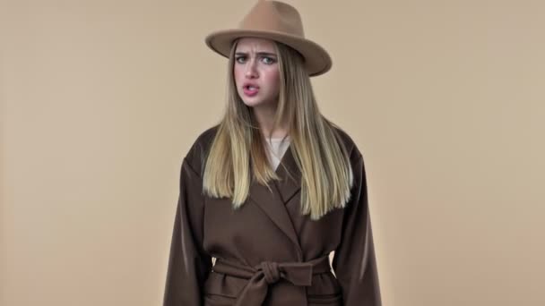 一个戴着帽子和外套的漂亮漂亮的年轻女人带着负面的情绪摇着头 说在演播室的米色背景下是不会被隔离的 — 图库视频影像