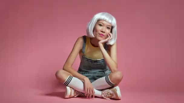 Молода Позитивна Азіатська Дівчина Сидить Ізольовано Рожевому Фоні Стіни Білому — стокове відео