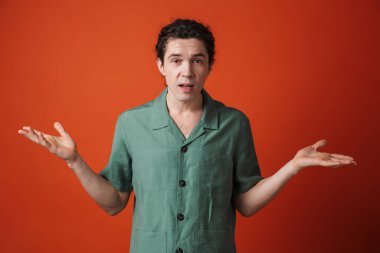 Kafası karışmış beyaz adamın görüntüsü kırmızı arka planda izole edilmiş kameraya öfkesini ifade ediyor.