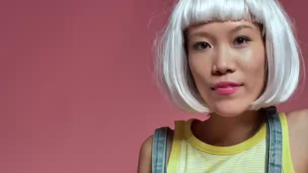 Jong Positief Aziatisch Meisje Geïsoleerd Roze Muur Achtergrond Wit Pruik — Stockvideo