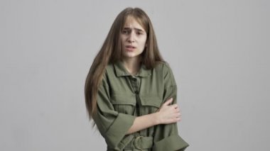 Gri duvar arkasında yalnız poz veren üzgün genç kız.