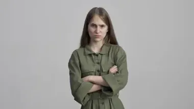 Gri duvar arkasında yalnız poz veren güzel, ciddi genç bir kız hayır diyor.