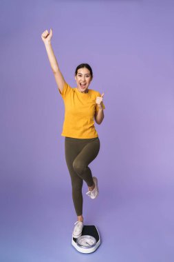 Menekşe arkaplan üzerinde izole bir şekilde duran neşeli, genç ve güzel bir sporcunun boyu.