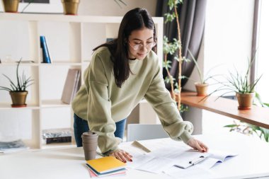 Güzel, mutlu, iyimser bir kız öğrencinin evde ders çalışmasının görüntüsü..