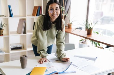 Güzel, mutlu, iyimser bir kız öğrencinin evde ders çalışmasının görüntüsü..