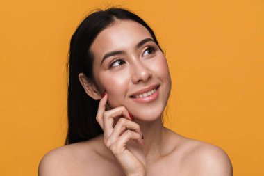 Beyaz tenli, yarı çıplak, mutlu gülümseyen bir kadının güzel portresi sarı arka planda soyutlanmış görünüyor.