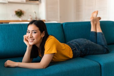 Evdeki kanepede güzel, mutlu, iyimser bir esmer kadının fotoğrafı..