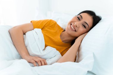 Güzel, mutlu, pozitif bir genç kadının evde, yatakta uzanmış görüntüsü..