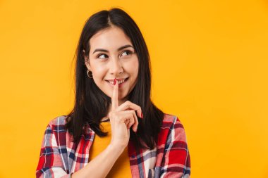 Kafkasyalı mutlu bir kadının sarı arka planda izole edilmiş bir şekilde düşünmesi ve bakması.