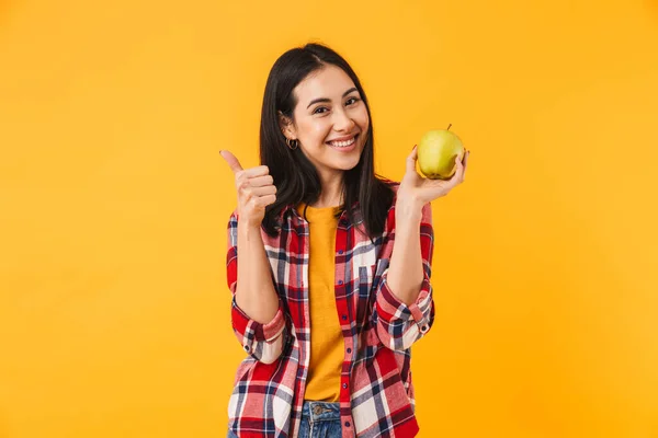 照片中 一个笑容满面的高加索女人伸出大拇指 把苹果夹在黄色的背景中 — 图库照片