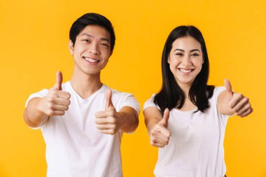 Sarı arka planda, gülümseyen ve el kol hareketi yapan neşeli erkek ve kadının görüntüsü.