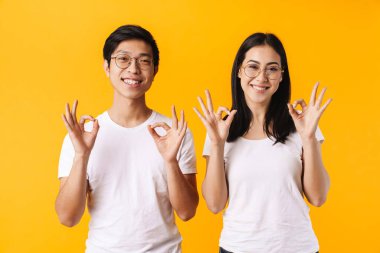 Neşeli adam ve kadının görüntüsü gülümseyen ve işaret eden tamam sarı arka planda izole edilmiş.