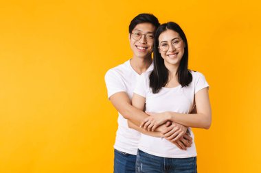 Sarı arka planda sarılıp gülen neşeli kadın ve erkeğin görüntüsü