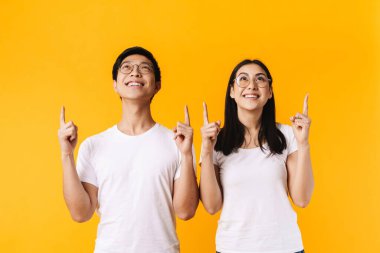 Gözlüklü gülümseyen adam ve kadının görüntüsü sarı arkaplan üzerinde parmaklarını yukarı kaldırarak izole edilmiş.