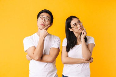 Çok uluslu kadın ve erkeğin sarı arka planda izole edilmiş bir şekilde düşündükleri ve baktıkları görüntüler.