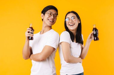 Komik, çok uluslu bir çiftin soda içip kahkahalarının sarı arka planda izole edilmiş hali.