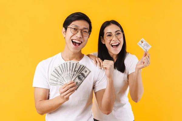兴奋的跨国夫妇在黄色背景下显示美元和信用卡的图片 — 图库照片