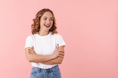 Pembe duvar arkasında yalnız poz veren mutlu genç bir kadın resmi..