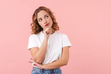 Düşünceli, genç ve güzel bir kadının pembe duvar arkasında yalnız poz vermesi..