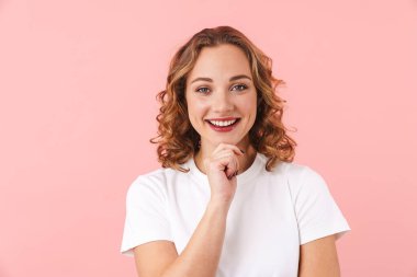 Pembe duvar arkasında yalnız poz veren neşeli, iyimser genç bir kadının görüntüsü..