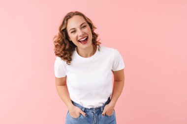 Pembe duvar arkasında yalnız poz veren mutlu genç bir kadın resmi..