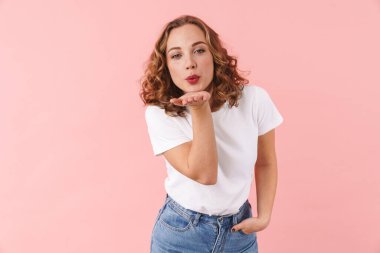 Mutlu ve güzel bir kadının pembe duvar arkasında izole bir şekilde poz verirken çekilmiş fotoğrafı. Öpücükler savururken..