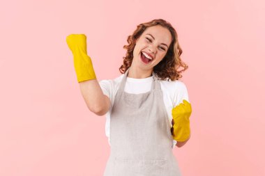 Güzel, mutlu ve güzel bir ev kadınının pembe duvar arkasında yalnız poz verirken çekilmiş fotoğrafı..