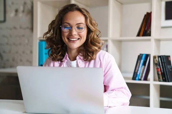 Foto Mulher Loira Alegre Usando Óculos Sorrindo Usando Laptop Enquanto — Fotografia de Stock