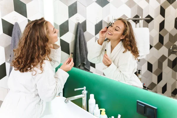 Mujer Joven Sonriente Usando Albornoz Haciendo Maquillaje Mientras Está Pie —  Fotos de Stock