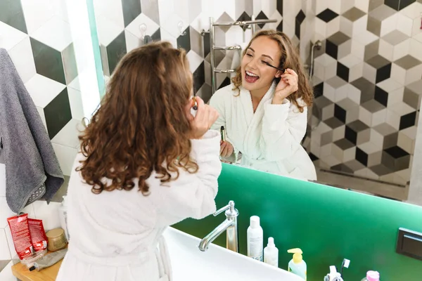 Smiling Young Woman Wearing Bathrobe Doing Makeup While Standing Mirror — Stock Photo, Image