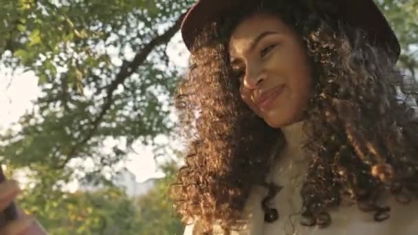 Молодая Улыбающаяся Африканская Девушка Шляпе Гуляет Зеленому Природному Парку Разговаривает — стоковое видео