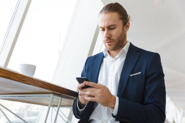 Ofiste cep telefonu kullanan yakışıklı, ciddi bir iş adamının resmi..