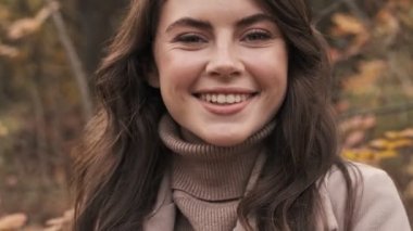 Yeşil doğa parkında kameraya bakan mutlu genç bir kız.