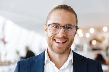 Yakışıklı, mutlu, neşeli, ofisteki genç iş adamının yan yana baktığı bir görüntü..