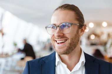 Yakışıklı, mutlu, neşeli, ofisteki genç iş adamının yan yana baktığı bir görüntü..