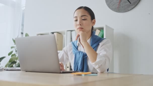 Una Joven Secretaria Asiática Reflexiva Enfocada Está Usando Computadora Portátil — Vídeos de Stock