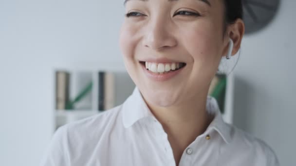 Eine Fröhliche Junge Asiatische Geschäftsfrau Mit Drahtlosen Kopfhörern Telefoniert Büro — Stockvideo