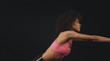 Sıska, Afro-Amerikan spor kıyafetli güzel bir kadının yan görüntüsü siyah arka planda izole edilmiş yamaçlar çiziyor.