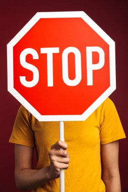 Kırmızı arka planda izole edilmiş, elinde dur tabelası tutan öfkeli, esmer, Afro-Amerikan kadın resmi