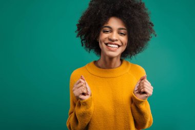 Yeşil arka planda tek başına duran, gülümseyen Afrikalı genç bir kadının portresi. Kameraya bakıyor, başarıyı kutluyor.