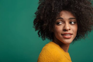 Oldukça memnun bir Afrikalı kıvırcık kadının koyu mavi duvar arkasında yalnız poz vermesi..