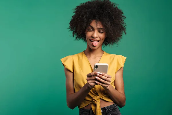 青い背景に隔離された携帯電話を使用している面白いアフリカ系アメリカ人女性の写真 — ストック写真