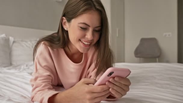 Smiling Young Attractive Girl Using Her Smartphone Lying Bed Home — Stock Video