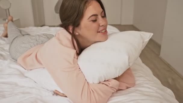 Una Atractiva Jovencita Sonriente Está Acostada Cama Abrazando Almohada Casa — Vídeos de Stock