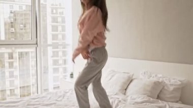 Mutlu, neşeli bir kız sabahları evde yatakta zıplıyor.