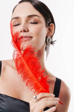 Beyaz arka planda izole edilmiş kırmızı tüylü aksesuar giyen, şehvetli, güler yüzlü, çekici bir kadının fotoğrafını çek.