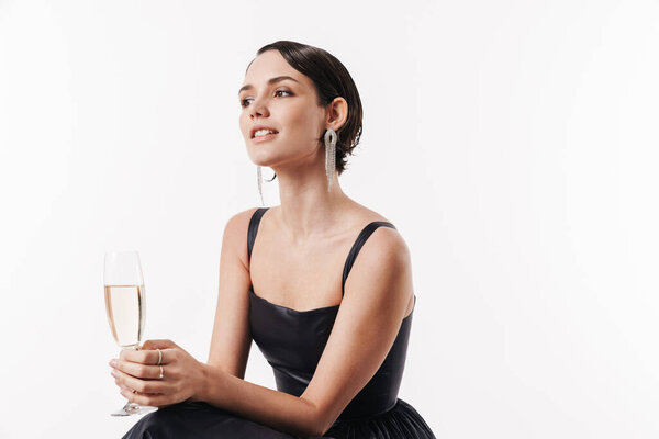 Image of charming young glamorous happy woman smiling and holding glass of champagne isolated over white background