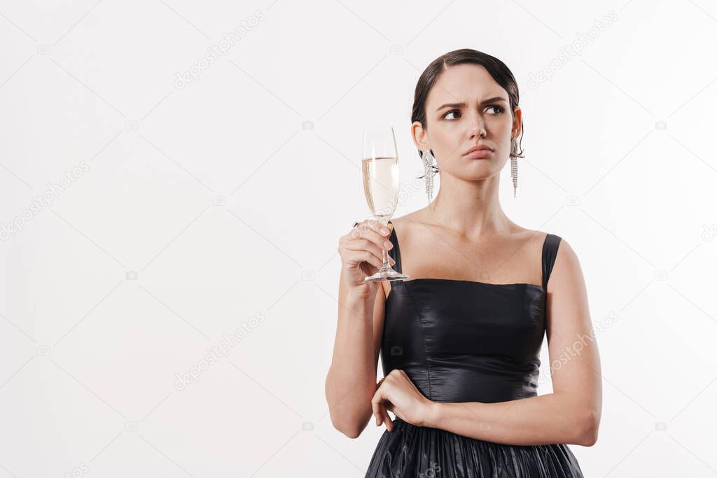 Image of charming young glamorous woman frowning and holding glass of champagne isolated over white background