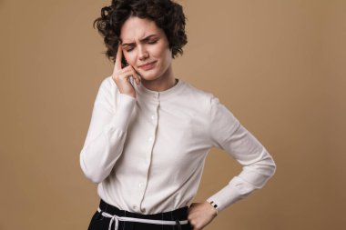 Kafkasyalı mutsuz bir kadının bej arka planda tapınağını ovalama görüntüsü.